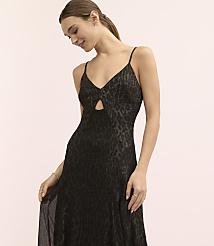 A woman wearing a black leopard-print slip dress poses against a plain light pink background. carousel Product Image 1