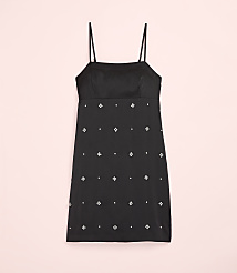 A black mini dress with small white floral embellishments is centered against a plain light pink background. carousel Product Image 4