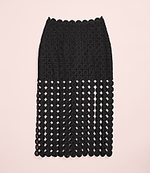 A black, intricately patterned skirt with a fringed bottom hangs against a plain light pink background. carousel Product Image 4