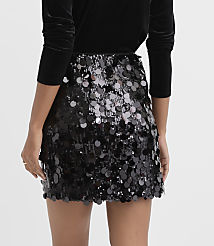 A person wears a black velvet top and a shimmering black sequined mini skirt against a plain white background. carousel Product Image 3