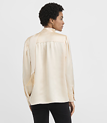 A woman wearing a champagne-colored satin blouse and black pants stands against a plain white background. carousel Product Image 3