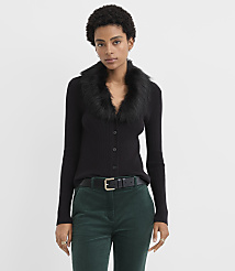 A woman wearing a black faux-fur collar cardigan and green corduroy pants stands against a plain white background. carousel Product Image 1