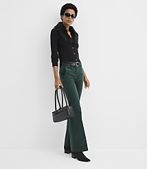 A woman wearing a black cardigan with a faux-fur collar, green corduroy trousers, and sunglasses stands against a plain white background. carousel Product Image 2
