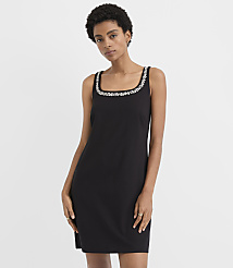 A woman wearing a black dress with a beaded neckline stands against a plain white background. carousel Product Image 1