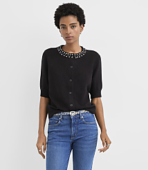 A woman wearing a black embellished cardigan and blue jeans stands against a plain light gray background. carousel Product Image 2