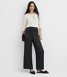 A woman wearing a white cable-knit sweater and wide-leg black trousers stands against a plain white background. carousel Product Image 1