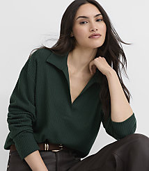 A woman wearing a dark green ribbed polo shirt and brown leather pants poses against a plain white background. carousel Product Image 1
