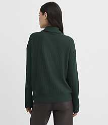 A woman wearing a dark green ribbed sweater and brown pants stands against a plain white background. carousel Product Image 3