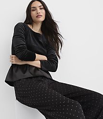 A woman wearing a black velvet top and polka-dot pants sits against a plain white background. carousel Product Image 1