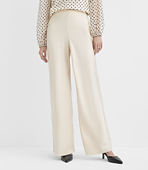 A person wears a polka-dot blouse and wide-leg cream trousers with black pointed heels against a plain white background. carousel Product Image 2