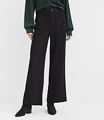A person wearing a green top, black wide-leg trousers with embellished pockets, and black ankle boots stands against a plain white background. carousel Product Image 2