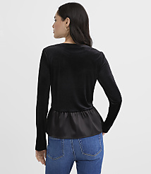 A woman wearing a black velvet top with a satin hem and blue jeans stands against a plain light gray background. carousel Product Image 3