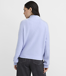 A woman wearing a light purple ribbed sweater and dark grey pants stands against a plain white background. carousel Product Image 3