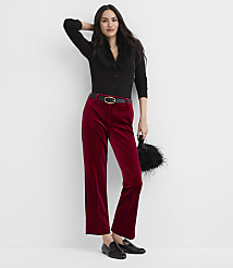 A woman wearing a black faux-fur collar top and red velvet trousers stands against a plain white background. carousel Product Image 1