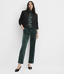 A woman wearing a black jacket, lace top, and green velvet trousers stands against a plain white background. carousel Product Image 1