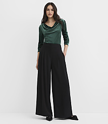 A woman wearing a green velvet top and wide-leg black trousers stands against a plain white background. carousel Product Image 1