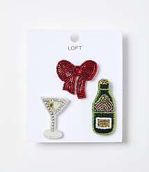 Three beaded brooches&mdash;a red bow, a champagne glass, and a green bottle&mdash;are displayed on a white card against a plain white background. carousel Product Image 1