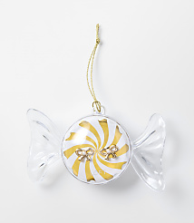 A clear, candy-shaped ornament with a gold and white swirl center and small bows sits against a plain white background. carousel Product Image 1