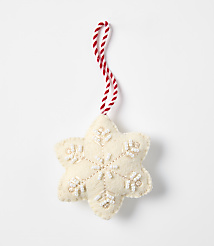 A cream-colored felt snowflake ornament with white bead accents and a red-and-white twisted string hangs against a plain white background. carousel Product Image 1