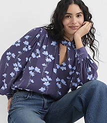 A woman wearing a purple floral blouse and blue jeans poses against a plain white background. carousel Product Image 1