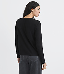 A woman wearing a black long-sleeved shirt and dark grey trousers stands against a plain white background. carousel Product Image 4