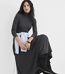 A woman wearing a charcoal grey turtleneck dress and black boots sits against a plain white background. carousel Product Image 2