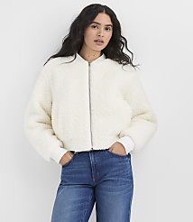 A woman wearing a white fuzzy jacket and blue jeans stands against a plain white background. carousel Product Image 1
