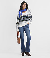 A woman wearing a patterned sweater, blue scarf, and flare jeans stands against a plain white background. carousel Product Image 3