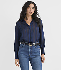 A woman wearing a navy blue striped blouse and blue jeans stands against a plain white background. carousel Product Image 1