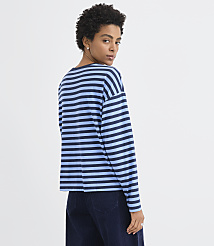 A woman wearing a blue and navy striped long-sleeve shirt and dark trousers stands against a plain white background. carousel Product Image 3