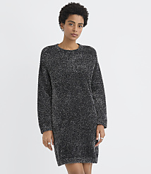 A woman wearing a shimmering dark grey knit dress stands against a plain white background. carousel Product Image 1
