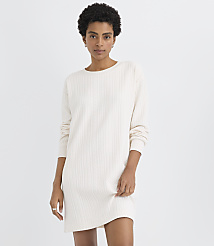 A woman wearing a white cable-knit sweater dress stands against a plain, light-colored background. carousel Product Image 1
