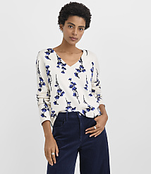 A woman wearing a white floral-print sweater and navy corduroy pants stands against a plain white background. carousel Product Image 1