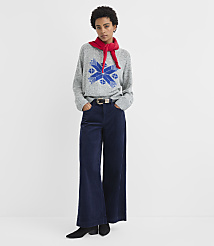 A woman wearing a grey patterned sweater, red scarf, and wide-leg navy trousers stands against a plain white background. carousel Product Image 3