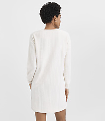 A woman with curly dark hair is seen from behind wearing a white cable-knit sweater dress against a plain light gray background. carousel Product Image 3