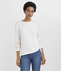 A woman wearing a white long-sleeved shirt and blue jeans stands against a plain white background. carousel Product Image 2