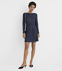 A woman wearing a navy blue long-sleeved dress and black heels stands against a plain white background. carousel Product Image 1