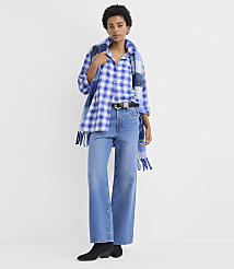 A woman wearing a blue plaid shirt, wide-leg jeans, and black boots stands against a plain white background. carousel Product Image 2
