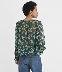 A woman wearing a green floral print blouse and blue jeans stands against a plain white background. carousel Product Image 3