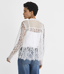 A woman wearing a white lace top and blue jeans stands against a plain white background. carousel Product Image 4