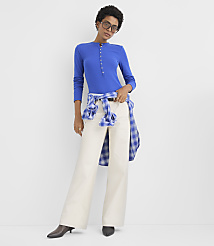 A woman wearing a blue long-sleeved top and wide-leg white pants stands against a plain white background. carousel Product Image 2
