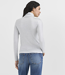 A woman wearing a grey turtleneck and blue jeans stands against a plain white background. carousel Product Image 3