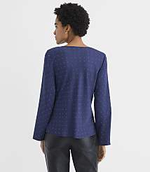 A woman with curly hair wearing a navy blue polka-dot blouse and black leather pants stands against a plain white background. carousel Product Image 3