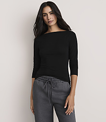 A woman wearing a black long-sleeved shirt and grey sweatpants stands against a plain, light-colored background. carousel Product Image 1