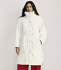 A woman wearing a long, white fuzzy coat and red pants stands against a plain, light-colored background. carousel Product Image 1