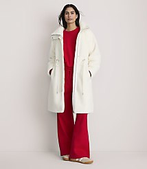 A woman wearing a long white fuzzy coat over a red outfit stands against a plain, light-colored background. carousel Product Image 2