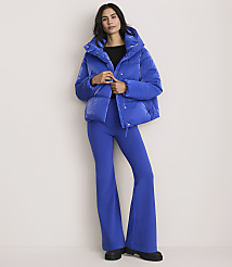 A woman wearing a bright blue puffer jacket and matching flared trousers stands against a plain, light-colored background. carousel Product Image 2