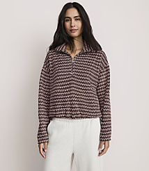 A woman wearing a patterned maroon and white quarter-zip pullover and light grey sweatpants stands against a plain, light-colored background. carousel Product Image 1
