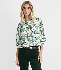 A woman wearing a green and white floral print blouse and dark green corduroy pants stands against a plain white background. carousel Product Image 1