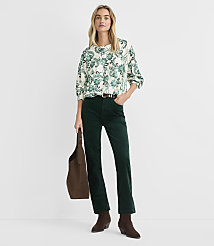 A woman wearing a patterned blouse and dark green corduroy pants stands against a plain white background. carousel Product Image 2